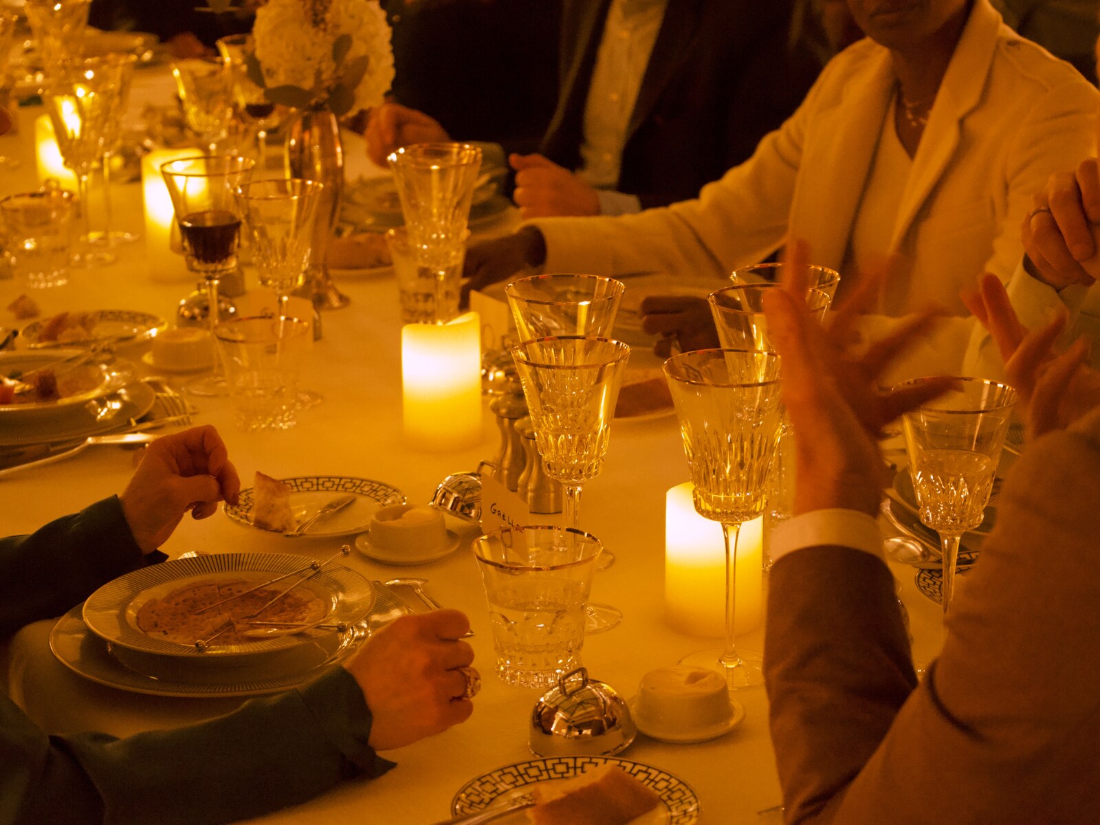 Dîner assis aux chandelles · convives à table, cristal et argenterie, lumière de bougies