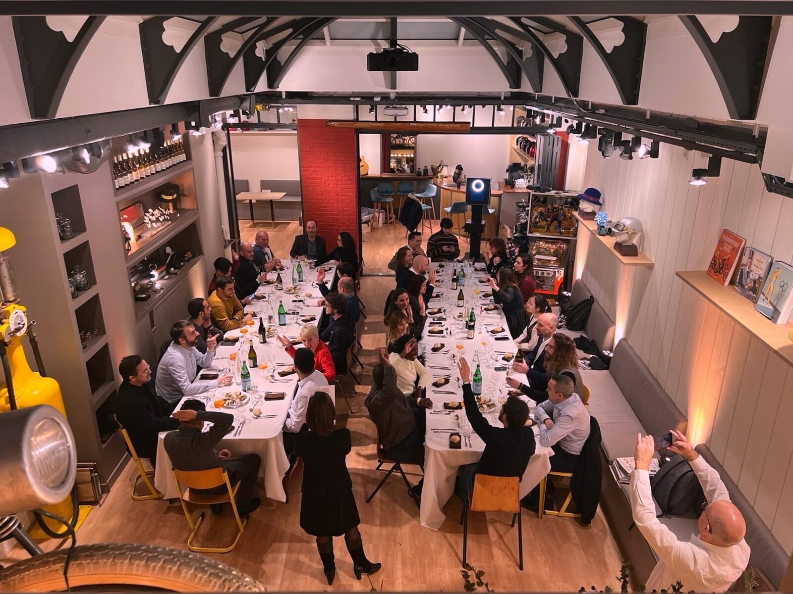 Grande tablée en dîner assis sous la verrière · convives à table, service en cours